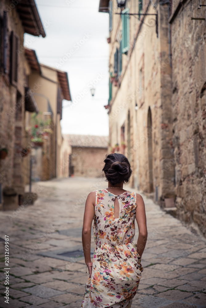 Young asian girl walking in Monticchiello town on summer day. Amazing promenade with traditional old stone houses - Tuscany, Italy, Europe Young asian girl walking in Monticchiello town on summer day. Amazing promenade with traditional old stone houses - Tuscany, Italy, Europe