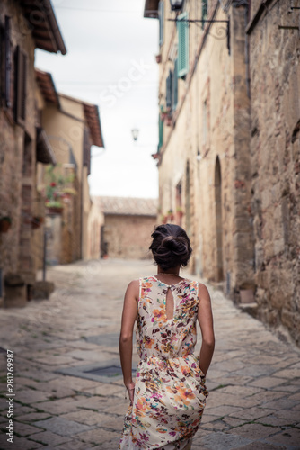Young asian girl walking in Monticchiello town on summer day. Amazing promenade with traditional old stone houses - Tuscany, Italy, Europe
