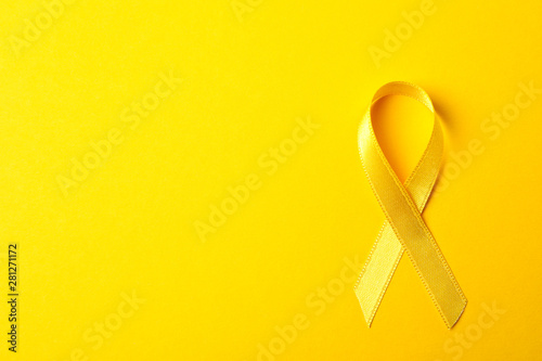 Yellow awareness ribbon on color background, space for text