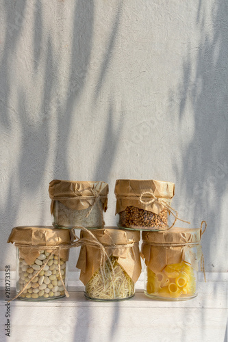 Cereals in glass jars on a light background with a shadow. Eco storage, zero waste