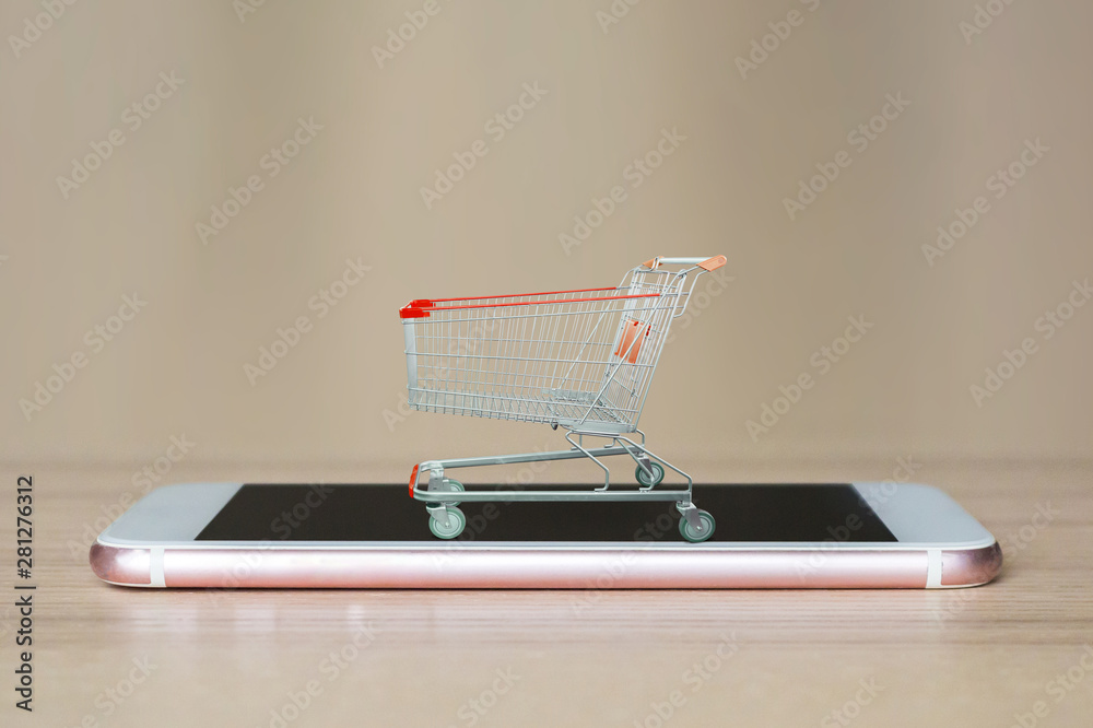 shopping cart on mobile smartphone on wood table