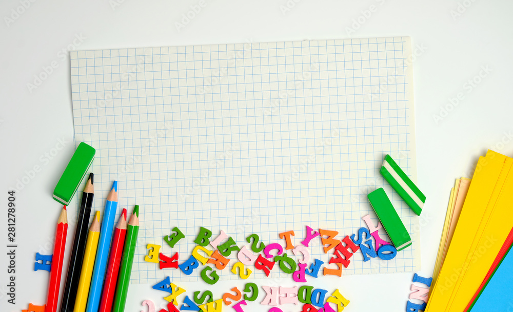 Fototapeta premium school supplies: multicolored wooden pencils, notebook, colored paper and blank white sheet in a check-box