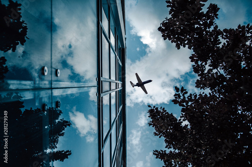 Shot of airplane flying above glass office buildings. Airplane flying over the city skyscrapers. Tall city buildings and a plane flying overhead.