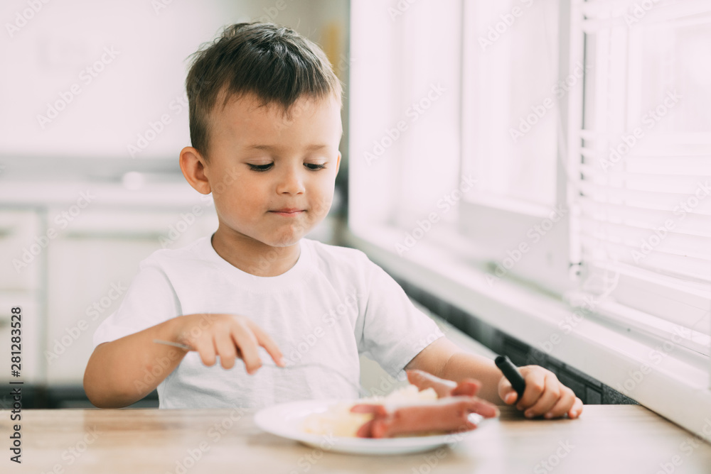 child in the kitchen eating sausage and mashed potatoes child in the kitchen eating sausage and mashed potatoes