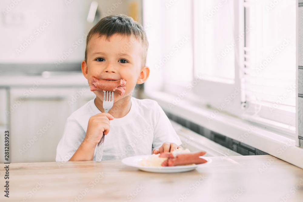 child in the kitchen eating sausage and mashed potatoes child in the kitchen eating sausage and mashed potatoes