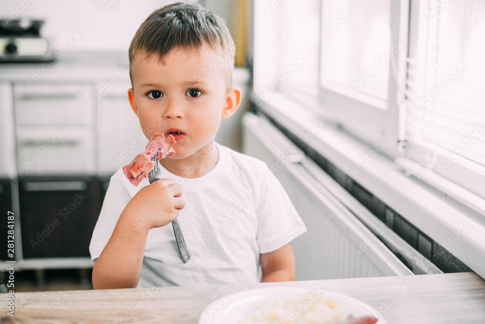 child in the kitchen eating sausage and mashed potatoes child in the kitchen eating sausage and mashed potatoes