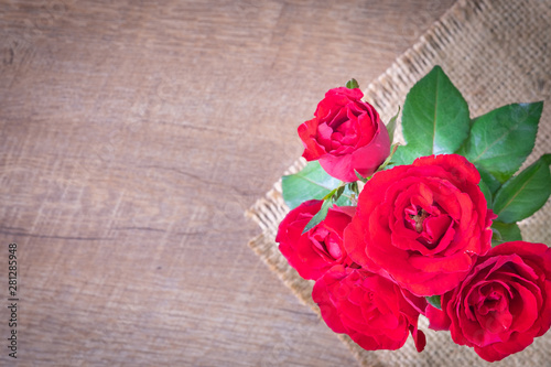Flat lay of Beautiful rose red on sack and wooden table with , copy empty space.