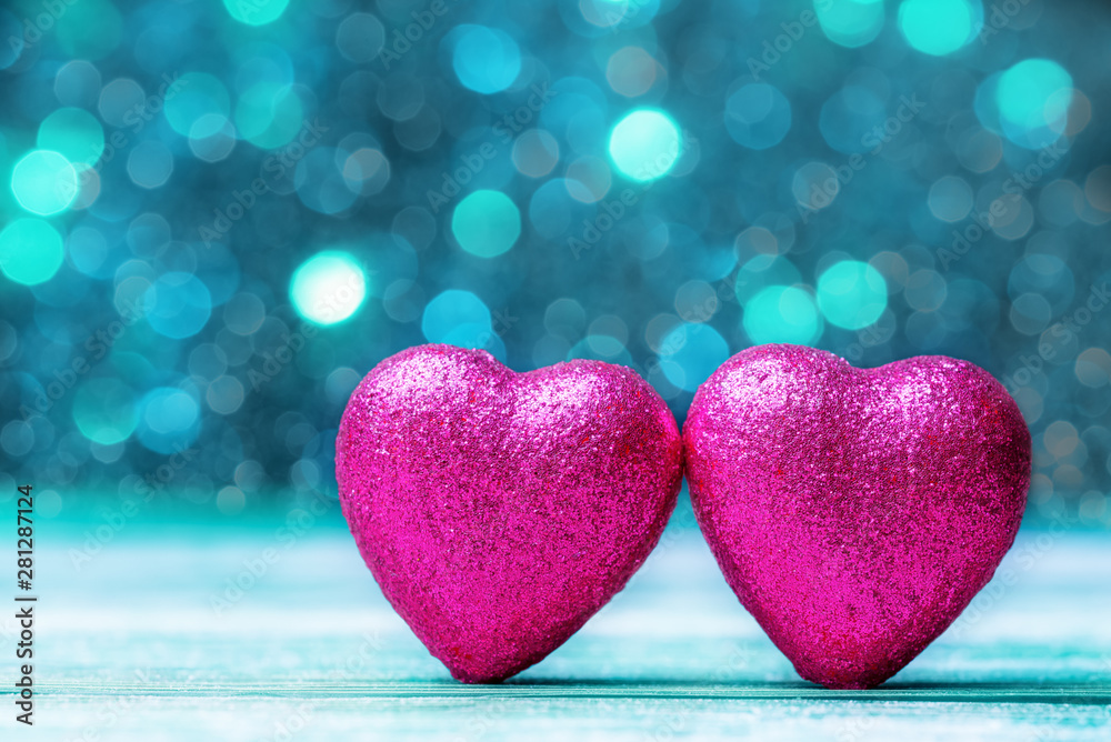 Two pink hearts against turquoise defocused lights. Valentines day concept