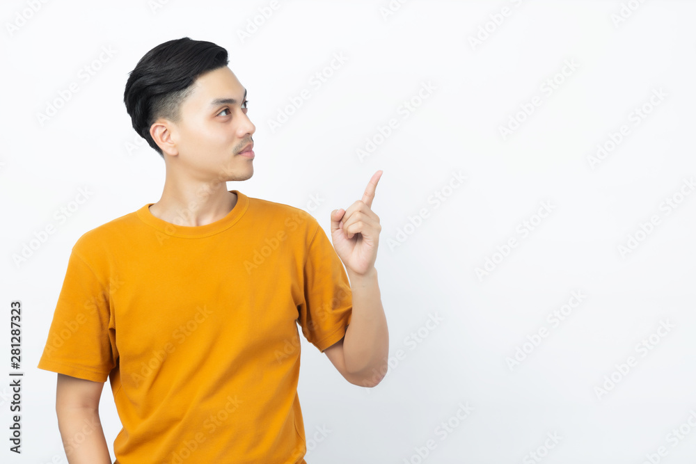 Happy healthy young Asian man smiling with his finger pointing up to copyspace on white background. Happy healthy young Asian man smiling with his finger pointing up to copyspace on white background.