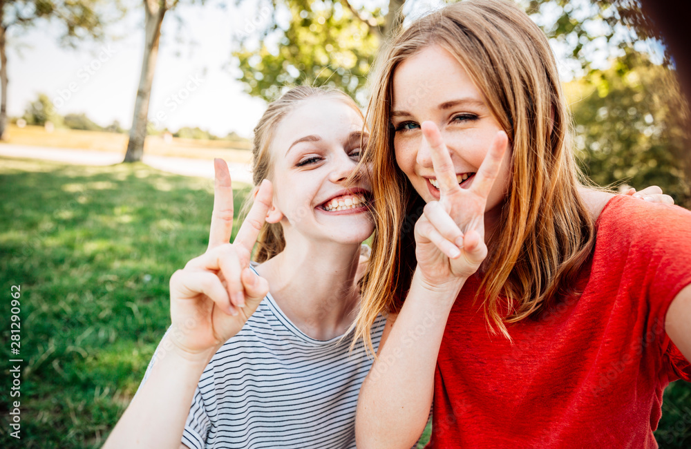 Two playful teenage girls making victory sign