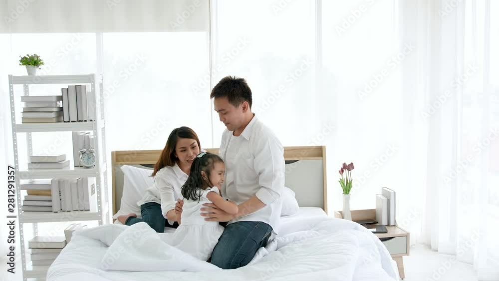 Asian family happy spending time together in the house. Father, mother and daughter, aged three enjoying playing on the bed. Slow motion Asian family happy spending time together in the house. Father, mother and daughter, aged three enjoying playing on the bed. Slow motion