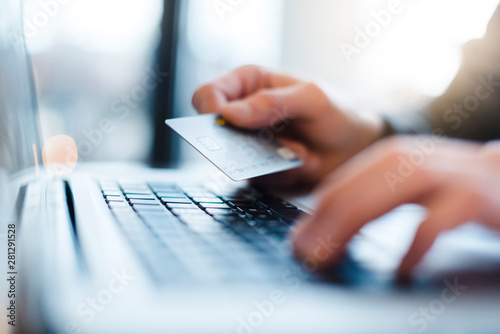 Man using laptop and holding credit card, close-up photo