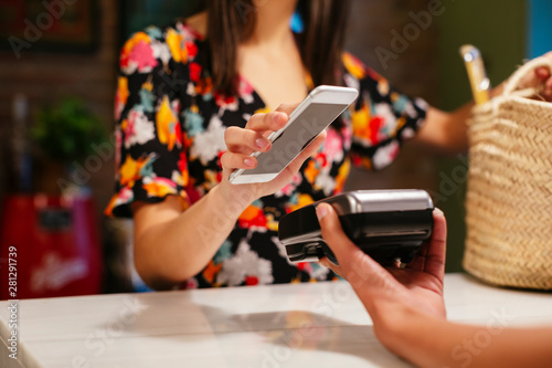 Close-up of customer paying cashless with smartphone at counter of a store photo