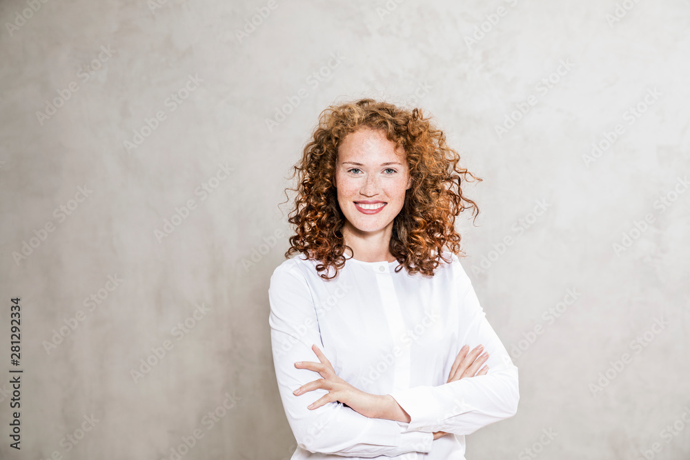 Portrait of laughing redheaded young woman with arms crossed