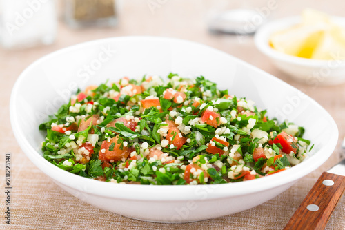 Fresh vegan Tabbouleh salad made of tomato, parsley, onion and couscous in bowl (Selective Focus, Focus one third into the salad)