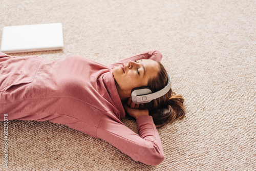 Woman lying on carpet wearing headphones photo