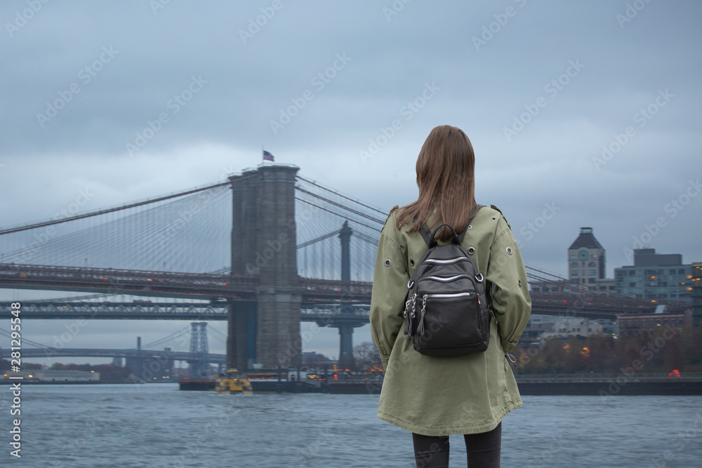  woman walks on the background of the Brooklyn Bridge.