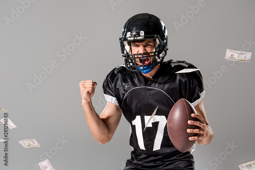 yelling American Football player with ball Isolated On grey with falling money