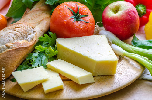 A horizontal shot of a delicious quick snack of a ploughman’s lunch with French bread mature cheese a fresh tomato and an apple. 
