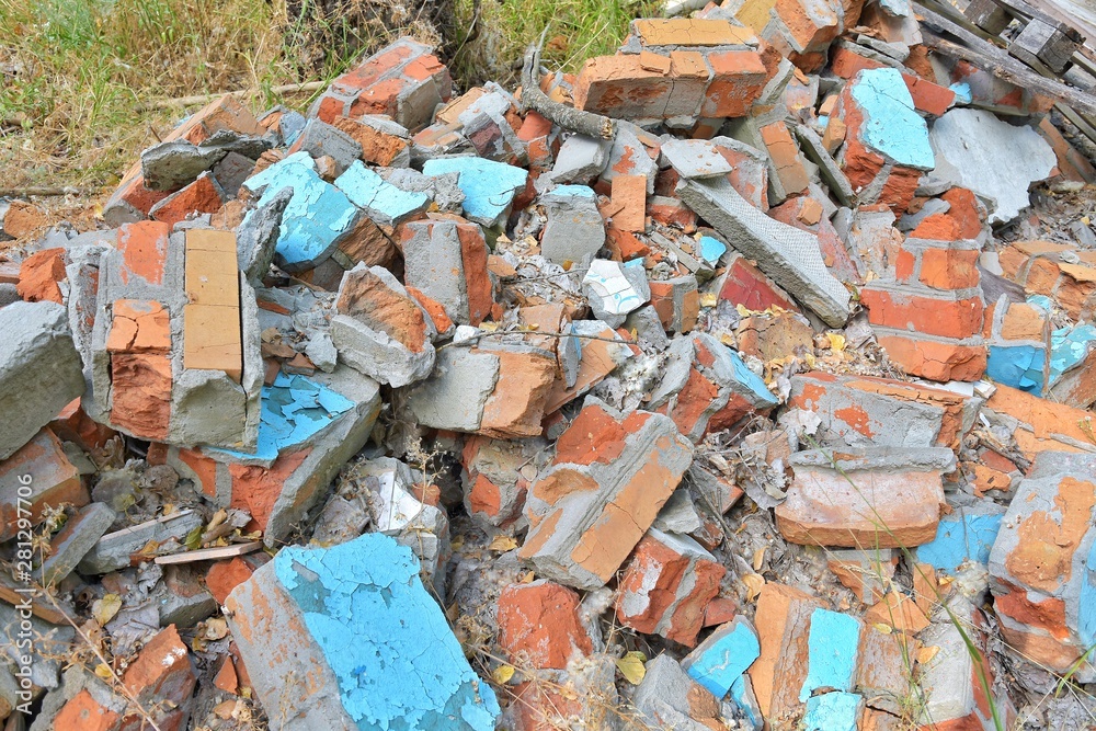 Pile of construction waste with old broken red bricks and broken boards. Rubbish from a ruined house with bricks pieces and old timber. Junk yard outdoor. Old building materials polluting environment