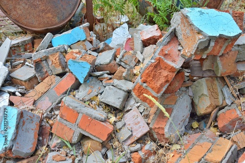 Pile of construction waste with old broken red bricks and broken boards. Rubbish from a ruined house with bricks pieces and old timber. Junk yard outdoor. Old building materials polluting environment