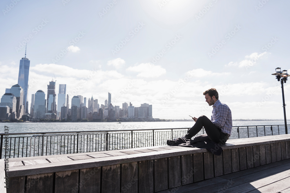 USA, man using tablet at New Jersey waterfront with view to Manhattan