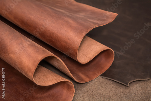 Rolls of natural brown and black leather. Materials for leather craft