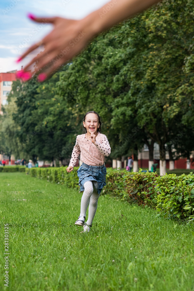 Little cheerful girl running through the grass.