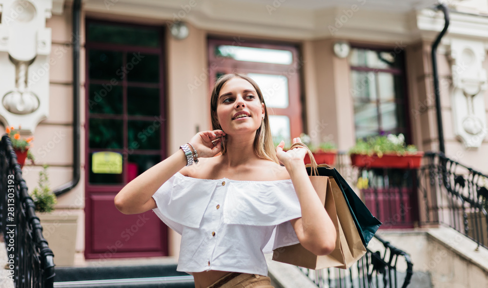 Young sharming shopaholic woman wearing in trendy clothes against shop background