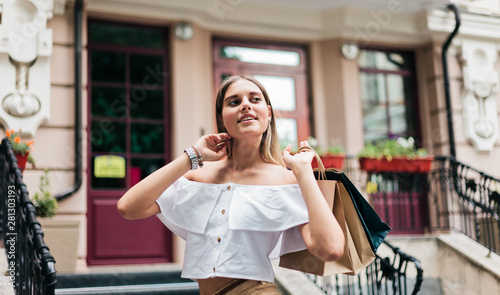 Young sharming shopaholic woman wearing in trendy clothes against shop background