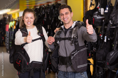 Man and woman in modern diving vest holding thumbs up