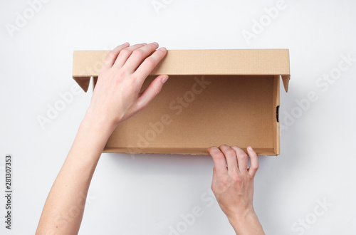 Female hands open empty cardboard box on gray background. Top view © splitov27