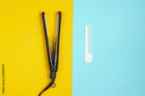 Minimalistic beauty and fashion still life. Comb and hair straightener on blue yellow background. Top view  flat lay