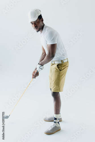 handsome african american sportsman playing golf on grey background