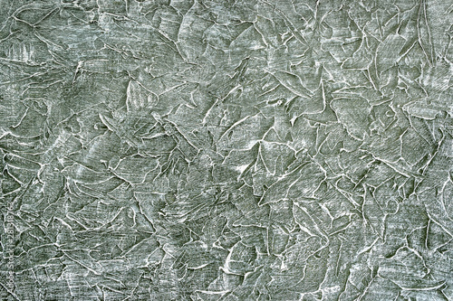 Rough dark textured surface is slightly painted with white paint. Abstract scrathed background pattern, acrylic paints. photo