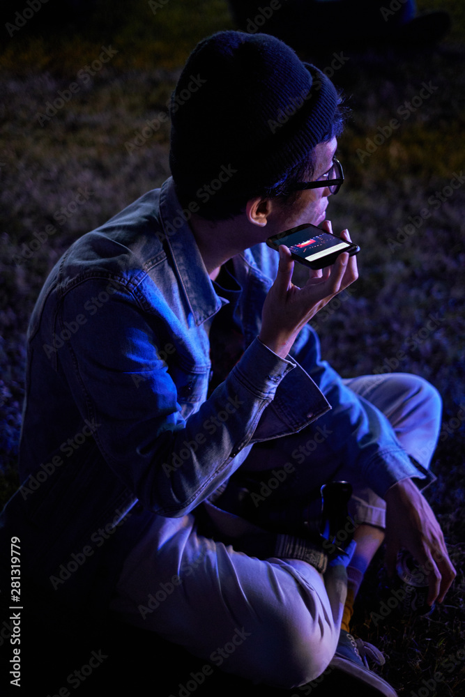 Asian young man holding mobile phone at the music festival scene Asian young man holding mobile phone at the music festival scene