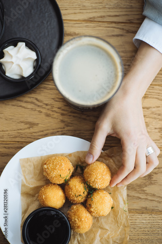 Woman taking cheese ball from dish photo