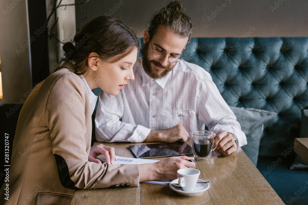 Businesswoman showing document to colleague in cafe Businesswoman showing document to colleague in cafe