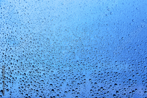 Water drops on glass, blue natural background