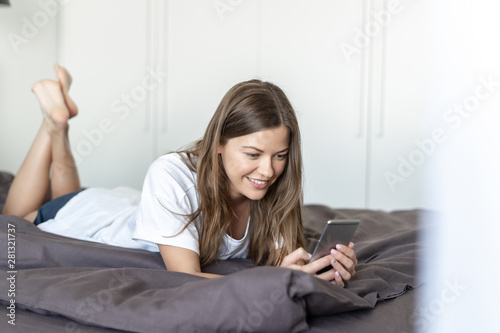 Young adult woman using smartphone in bed