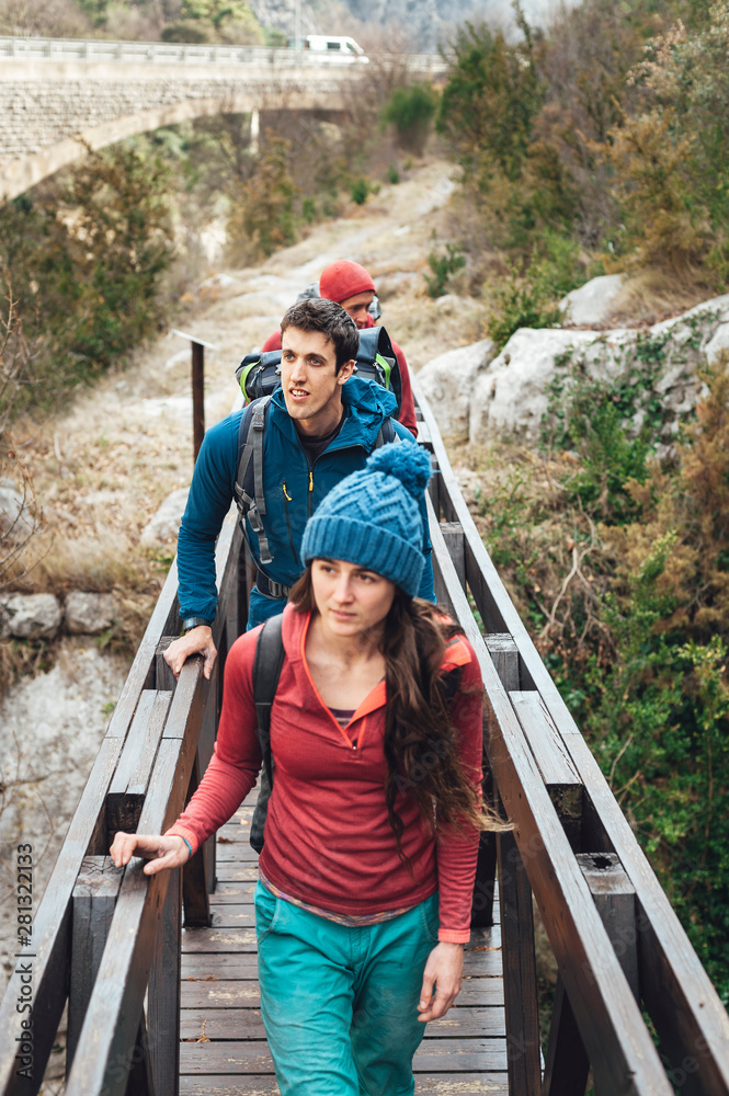 Group of backpackers walking through a wooden bridge over a river Group of backpackers walking through a wooden bridge over a river