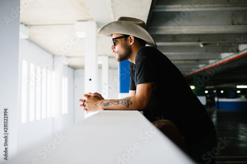 Modern man in hat standing on parking photo