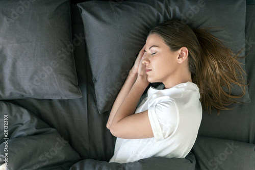 Young adult woman sleeping on bed in morning