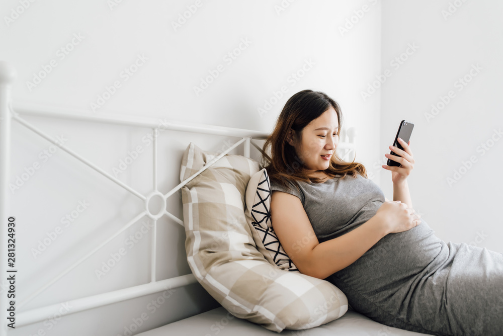 Pregnant woman using cell phone at home Pregnant woman using cell phone at home