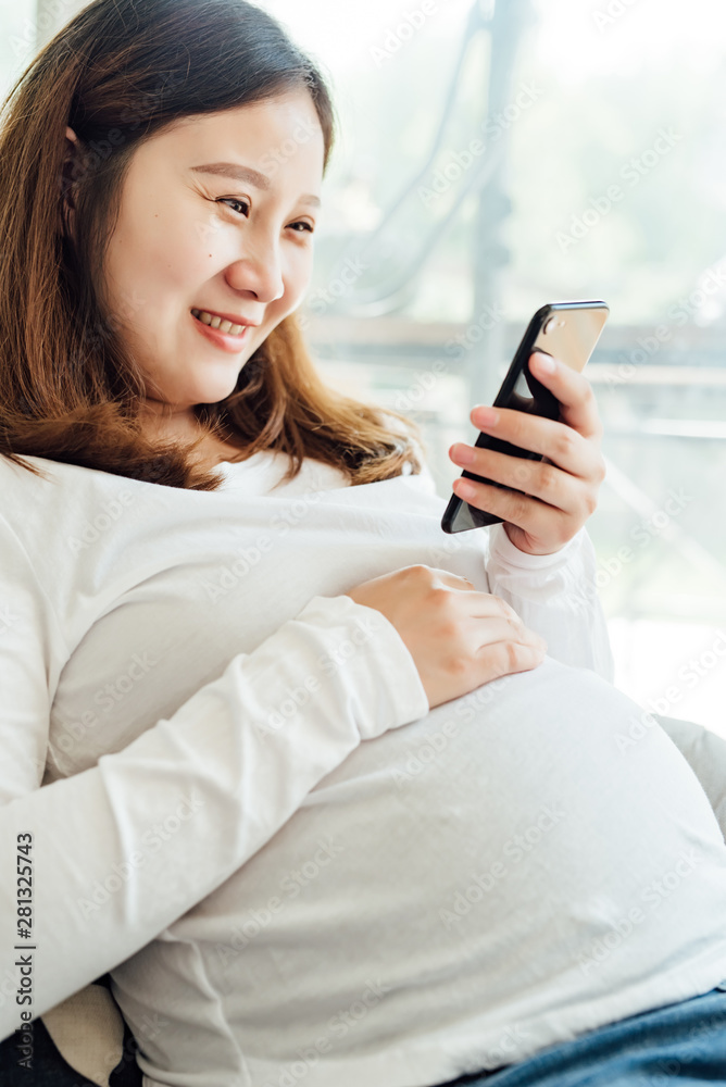 Pregnant woman using cell phone at home