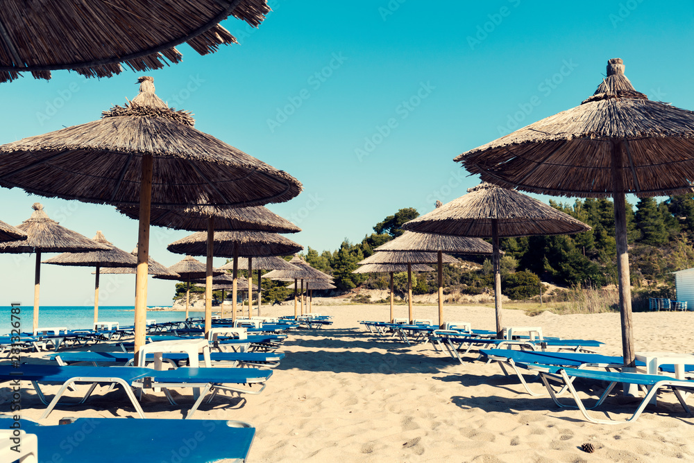 Straw umbrellas in rows with on a beautiful beach in Chalkidiki and no people Selective focus