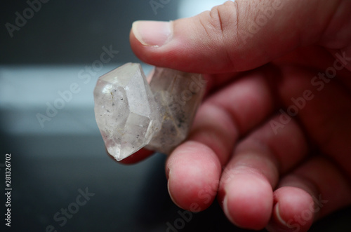 Beautiful Clear Quartz being held in woman's hand. Bright Quartz crystal, healing crystal being held in hand. Woman holding quartz tower, crisp colors in natural lighting. Vibrant meditation.