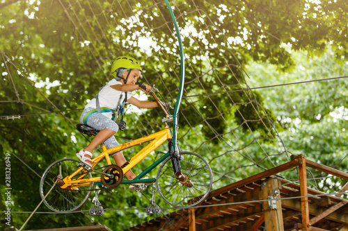 Happy school girl enjoying activity in a climbing adventure park on a summer day