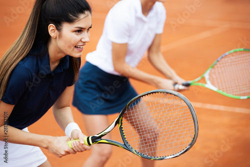 Young happy women friends playing tennis at tennis court © NDABCREATIVITY