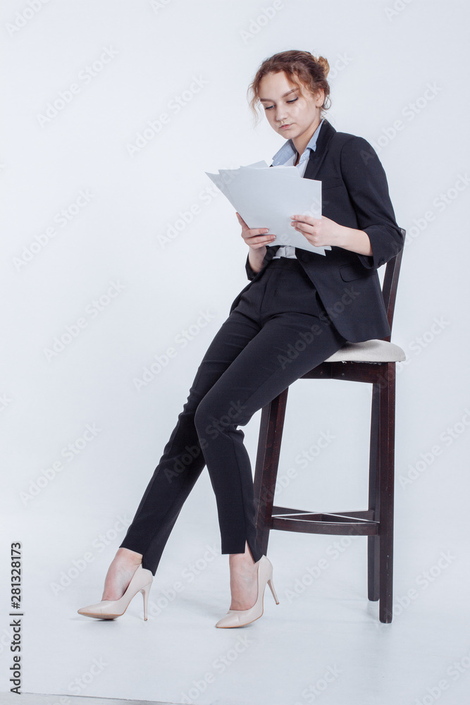 Young office worker girl in classic suit keeps clean sheets of paper isolated on white background. Cute financier lean on chair, holding clipboard in hands, thumbnail month's report in workplace. Young office worker girl in classic suit keeps clean sheets of paper isolated on white background. Cute financier lean on chair, holding clipboard in hands, thumbnail month's report in workplace.